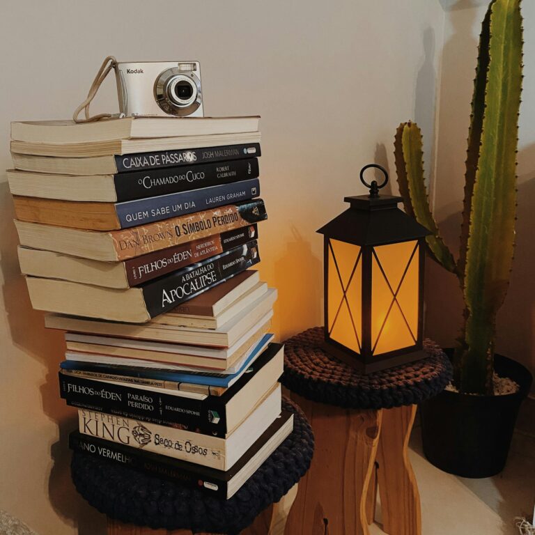 Aesthetic stack of books with vintage camera and glowing lantern, perfect for cozy home decor inspiration.